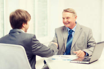 older man and young man shaking hands in office