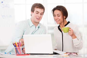 Obraz premium Young businessman and mixed race businesswoman with laptop