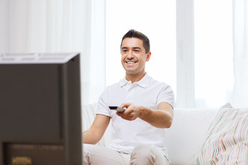 smiling man with remote control watching tv