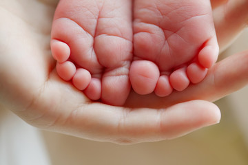 mother hold feets of newborn baby