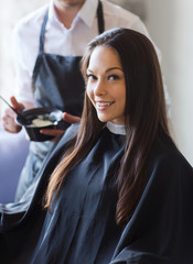 happy young woman coloring hair at salon
