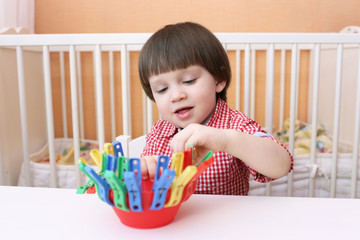 portrait of 2 years child playing with clothes pins