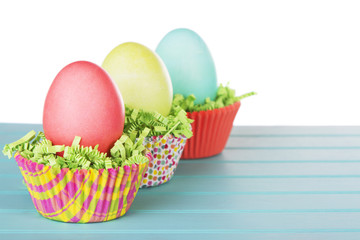 Fototapeta na wymiar Dyed Easter eggs in a nest of green grass confetti and cup cake