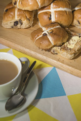 Hot cross buns with a cup of tea in the foreground