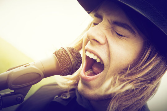 Man with long hair and hat shouting to microphone. Vintage music