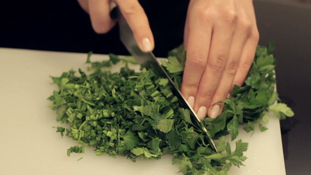 woman cuts fresh greens for salad