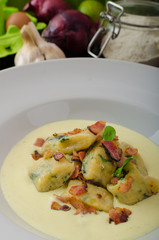 Spinach gnocchi with parmesan sauce topped with bacon