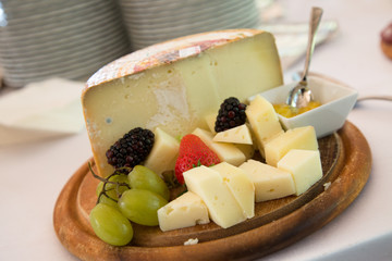 Formaggio e frutta su piatto di legno