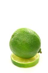 one whole lime fruit on top of a slice on a white background