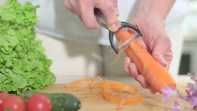 cleans a carrot with a knife for cleaning vegetables clouseup