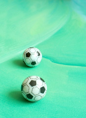 Toy soccer footballs on green canvas background.
