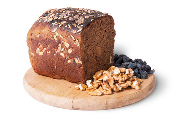 Bread with seeds on wooden board with raisins and nuts