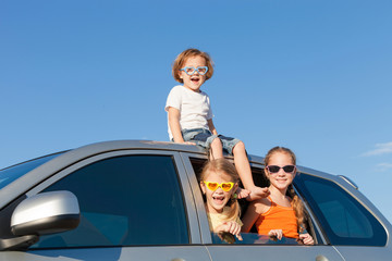 Happy brother and his two sisters are sitting in the car