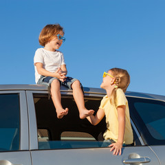 Happy brother and sister are sitting in the car