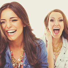 Two happy fashionable young women laughing