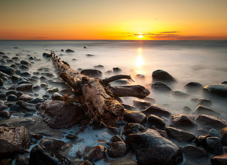 zachód słońca nad kamienistą plażą