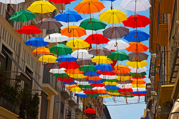 Fototapeta na wymiar Colorful umbrellas installed on the street in Spanish city.
