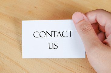 Contact us on paper card in hand, business concept