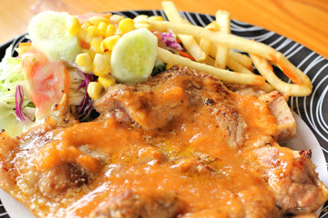 Steaks, french fries with vegetables salad on a plate.