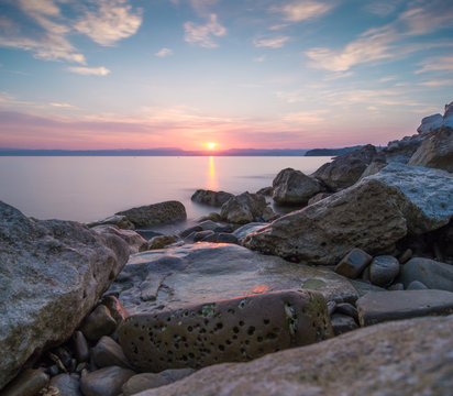 Fototapeta wschód słońca nad skalistą ,morską plażą