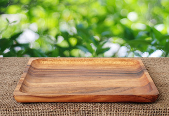 Empty wooden tray on table over blur trees with bokeh background