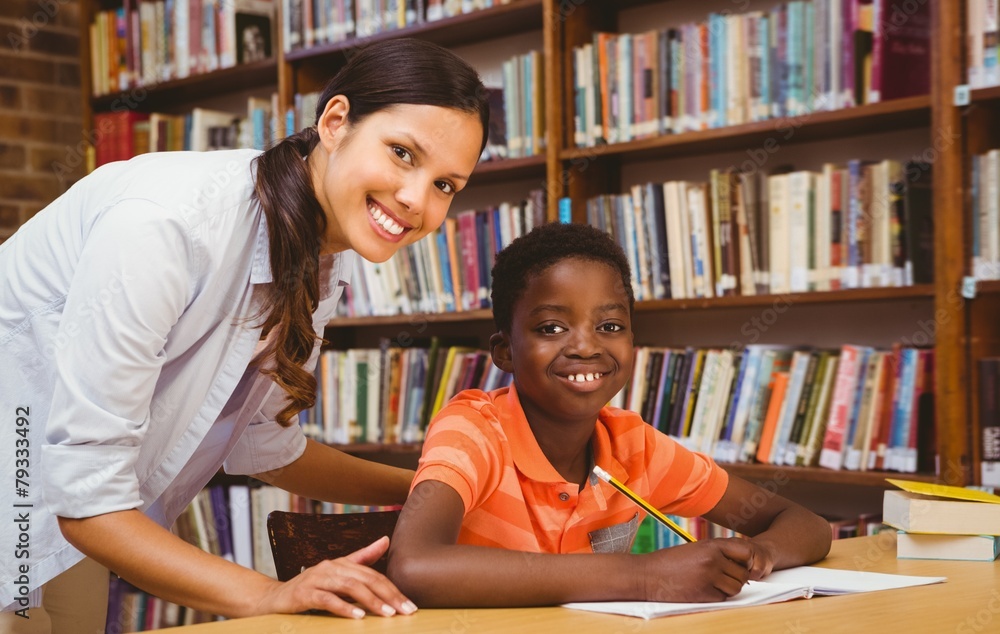 Poster teacher assisting boy with homework in library