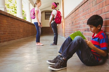 Schoolboy with friends in background at school corridor