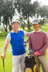 Golfing friends smiling at camera holding clubs