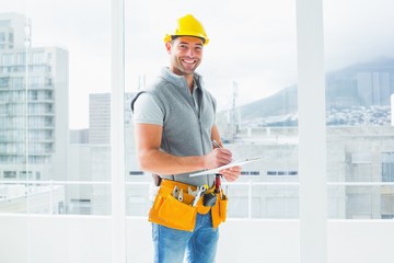 Manual worker writing on clipboard in building