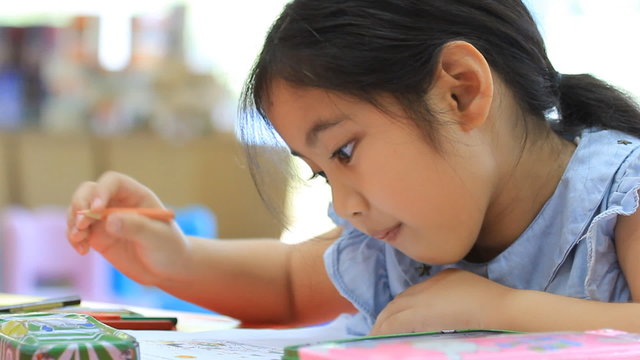 Little Asian girl painting a picture on the table