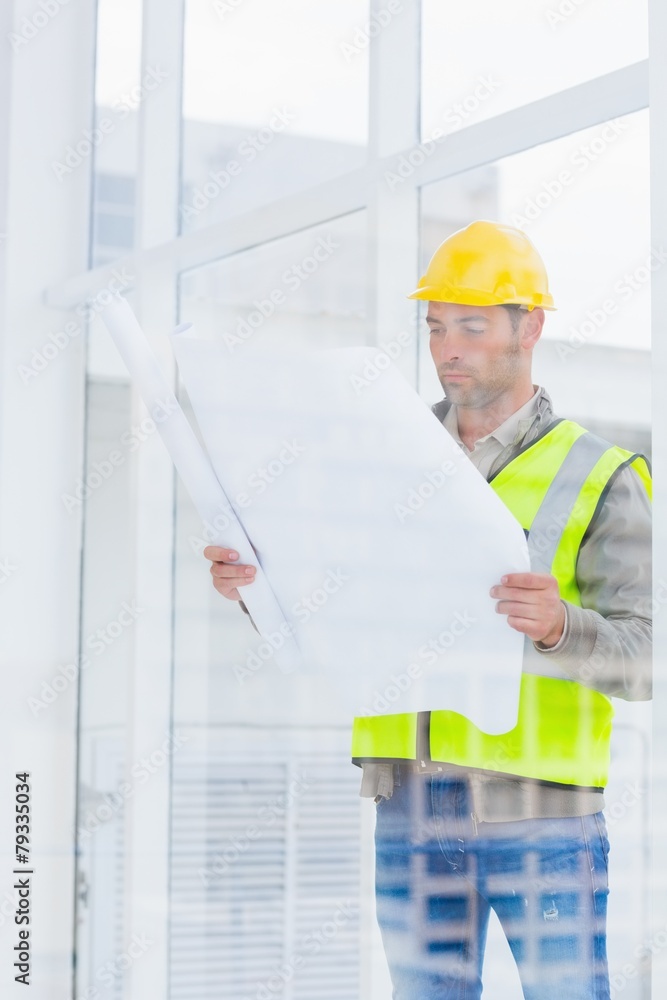 Poster architect reading blueprint in office