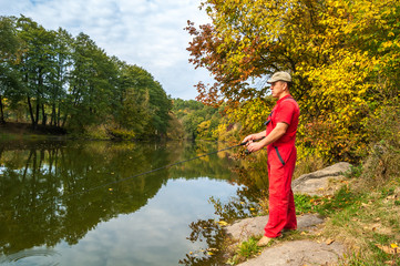 Fisherman on the river in the autumn forest.