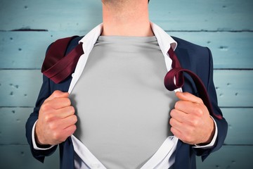 Composite image of businessman opening shirt in superhero style