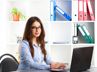 Young female general manager working at computer in her agency