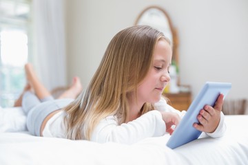 Little girl using tablet pc in the bed