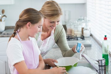 Happy mother and daughter washing up together