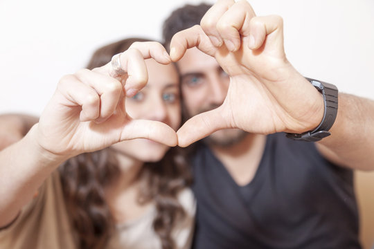 pretty young couple makes heart sign with his hands