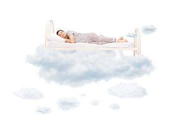 Young man sleeping on a comfortable bed in clouds