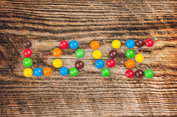 glazed color candy write word love isolated on wood background