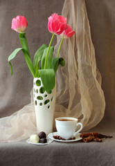 Pink tulips in a vase and cup of coffee.