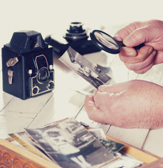 Old man hands, view photos with magnifying glass from the past