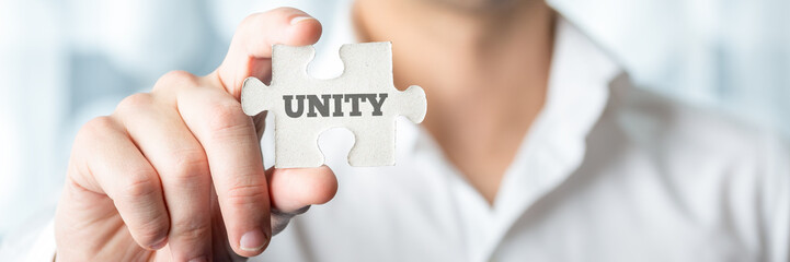 Businessman Showing Puzzle Piece with Unity Text