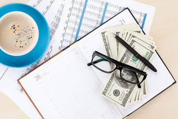 Office desk with reports, blank notepad and money cash