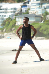 Young man standing on beach stretching exercise