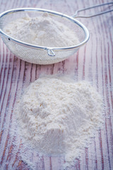 stack of flour and sieve on vintage wooden board