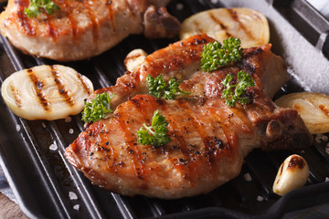 Two pork steak grilled with onions and garlic in a pan grill