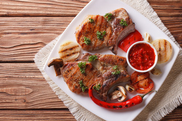 pork steak with grilled vegetables on plate, horizontal top view