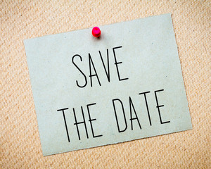Recycled paper note pinned on cork board.Save the Date Message.