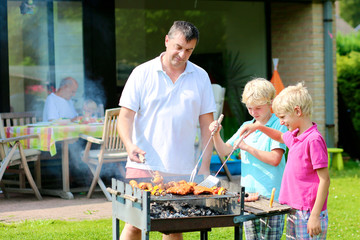 Father and sons grilling meat in the garden