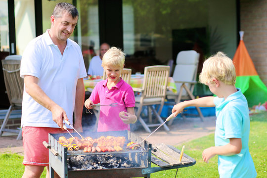 Father and sons grilling meat in the garden